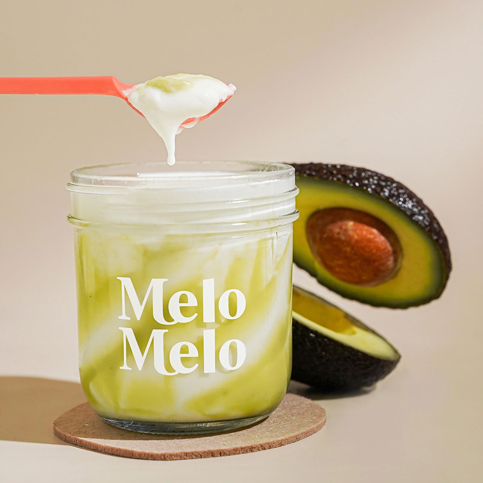 Avocado coconut jelly in glass jar, creamy coconut jelly with Avocado paste chunks, spoon lifting rich jelly, dripping texture, fresh Avocado fruit in background, clean beige background, soft natural light, premium dessert photography