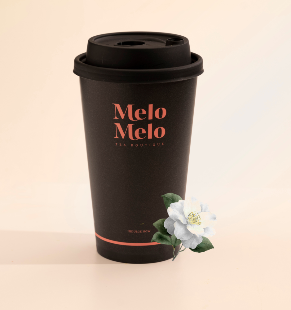 Minimalist product shot of a premium camellia tea boutique branded takeaway cup alongside loose leaf tea and dried camellia  flowers, highlighting a modern tea brand presentation.
