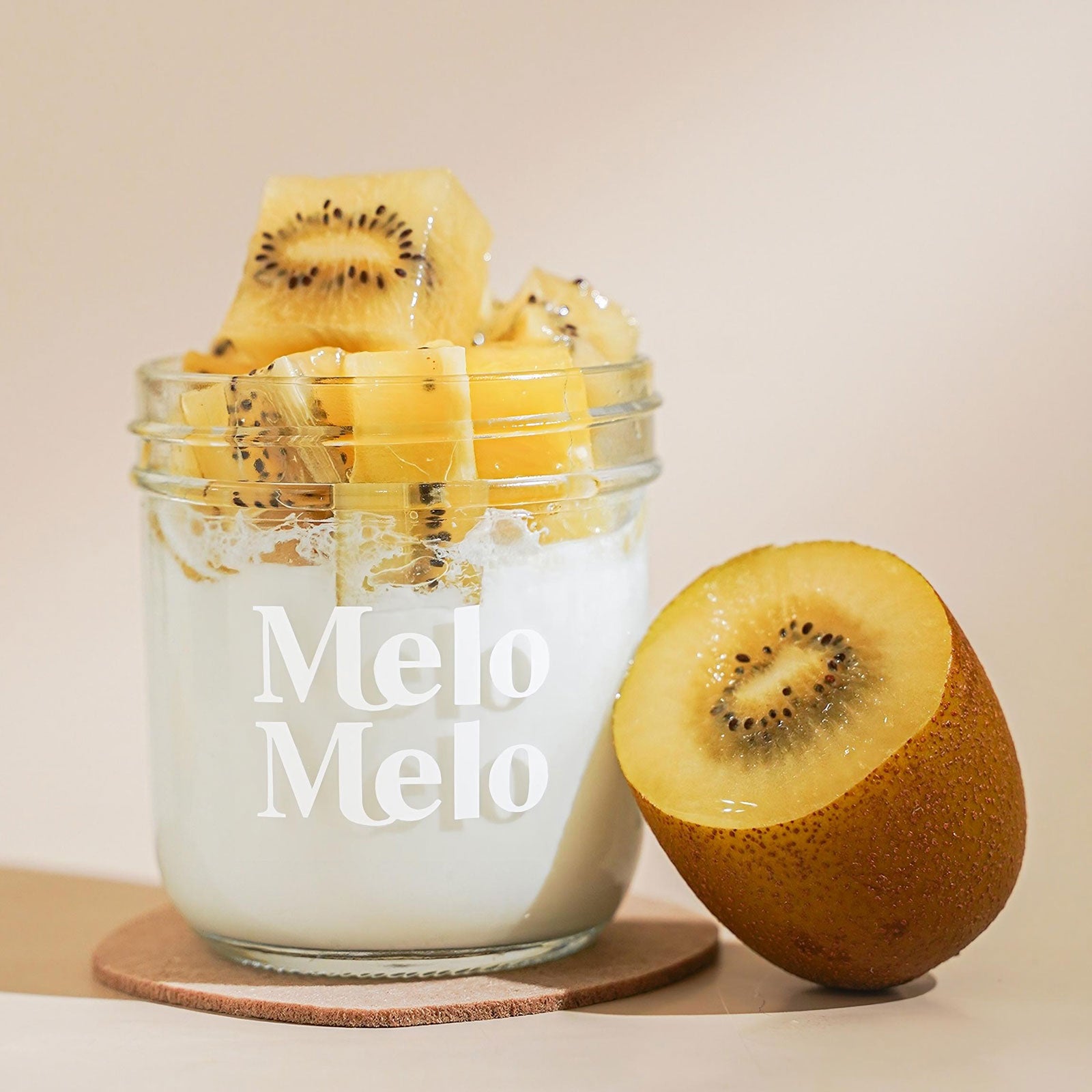 Golden Kiwi coconut jelly in a glass jar topped with vibrant fruit chunks, showcasing a smooth white coconut base and vivid Golden Kiwi pieces, fresh and visually striking tropical dessert.