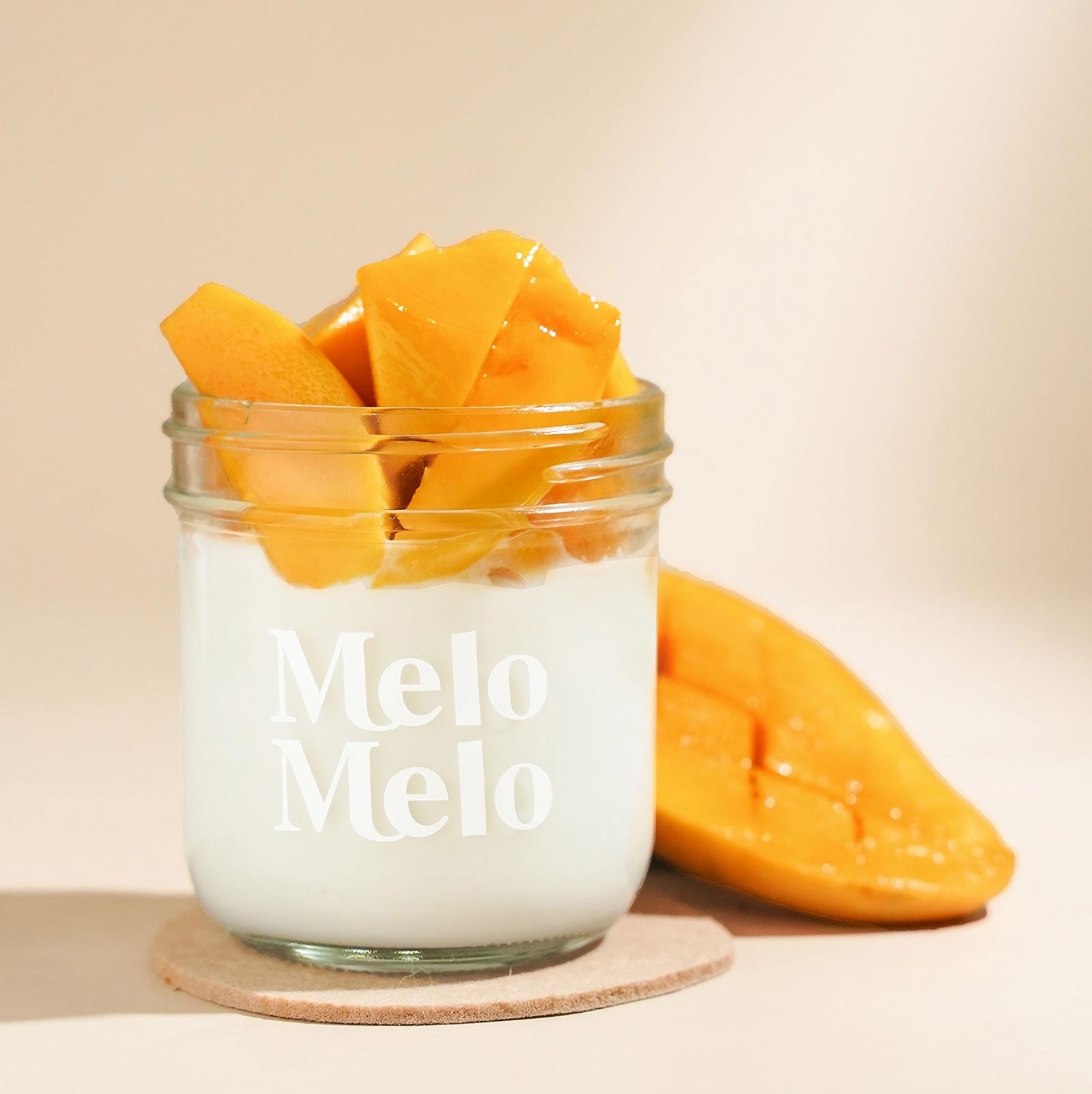 Mango coconut jelly in glass jar, creamy coconut layer with sweet mango chunks,  fresh mango beside, clean beige background, soft natural light, premium food photography