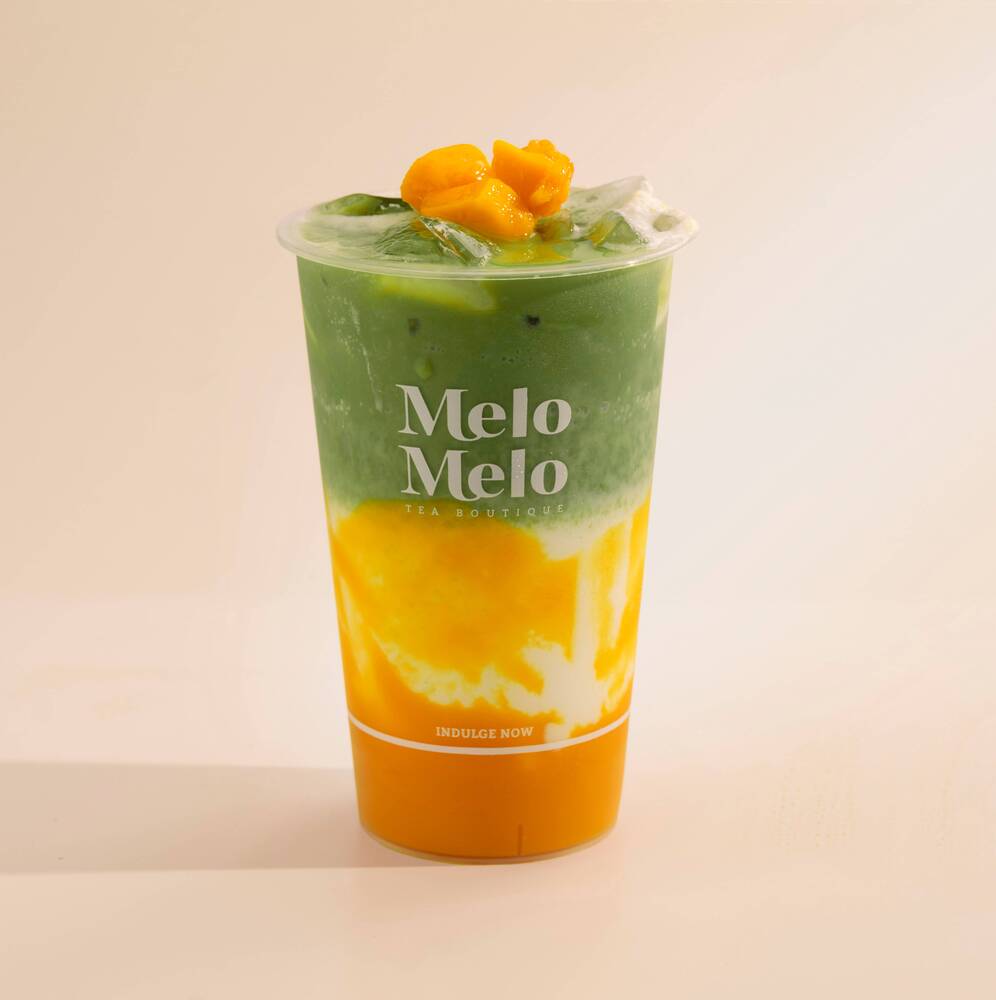 Layered mango matcha latte with real mango purée, creamy milk, and vibrant green matcha, topped with fresh fruit in a Melo Melo cup.