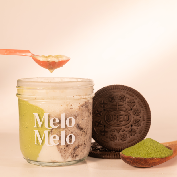Matcha Oreo Cream Cheese coconut jelly in glass jar, creamy coconut layer with soft Oreo pieces and rich matcha flavor  jelly base, spoon lifting silky jelly, dripping texture, Oreo and matcha  beside, clean beige background, soft natural light, premium food photography