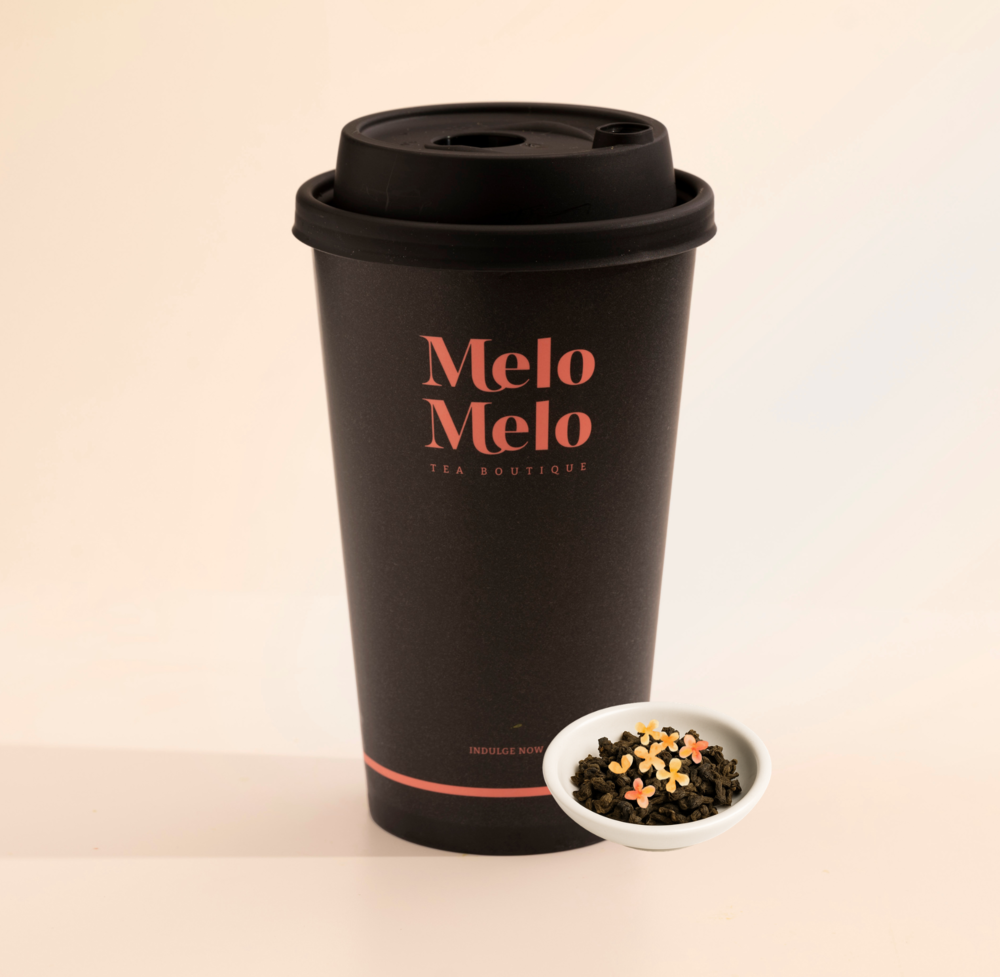 Minimalist product shot of a premium tea boutique branded takeaway cup alongside loose leaf tea and dried flowers, highlighting a modern tea brand presentation.