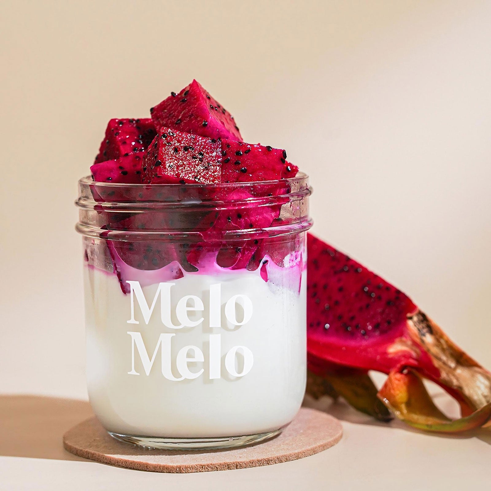 Red dragon fruit coconut jelly in a glass jar topped with vibrant fruit chunks, showcasing a smooth white coconut base and vivid magenta dragon fruit pieces, fresh and visually striking tropical dessert.