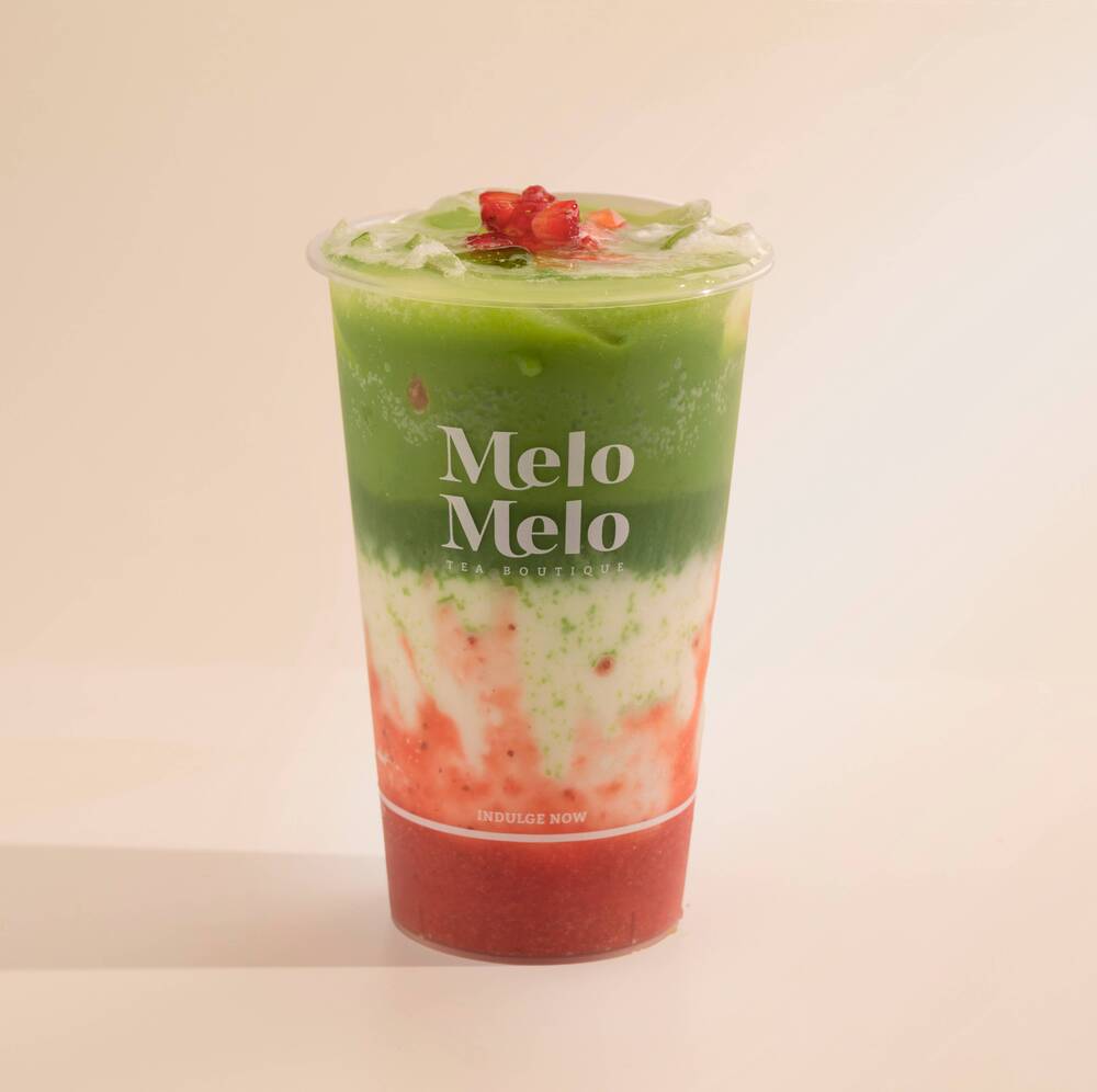 Layered strawberry matcha latte with real strawberry purée, creamy milk, and vibrant green matcha, topped with fresh fruit in a Melo Melo cup.