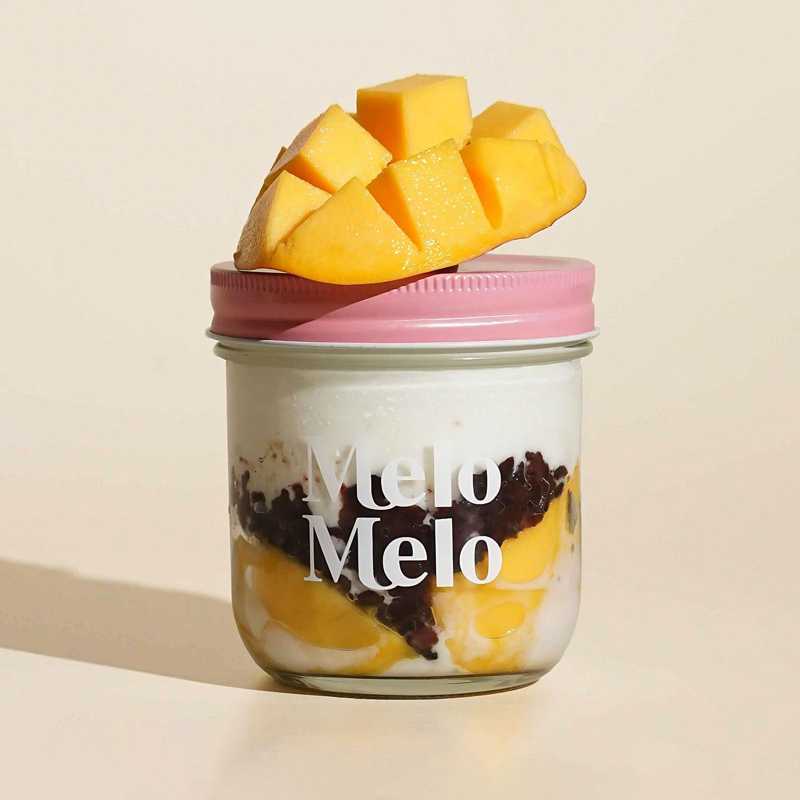 mango coconut jelly with black glutinous rice in glass jar, layered dessert with mango puree, coconut jelly and rice, fresh mango cubes on top, rich texture, clean beige background, soft natural light, premium food photography