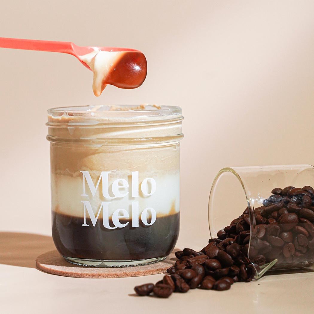 Triple Latte coconut jelly in glass jar, creamy coconut layer with creamy coffee milk jelly  base, spoon lifting silky jelly, dripping texture, fresh coffee bean  beside, clean beige background, soft natural light, premium food photography